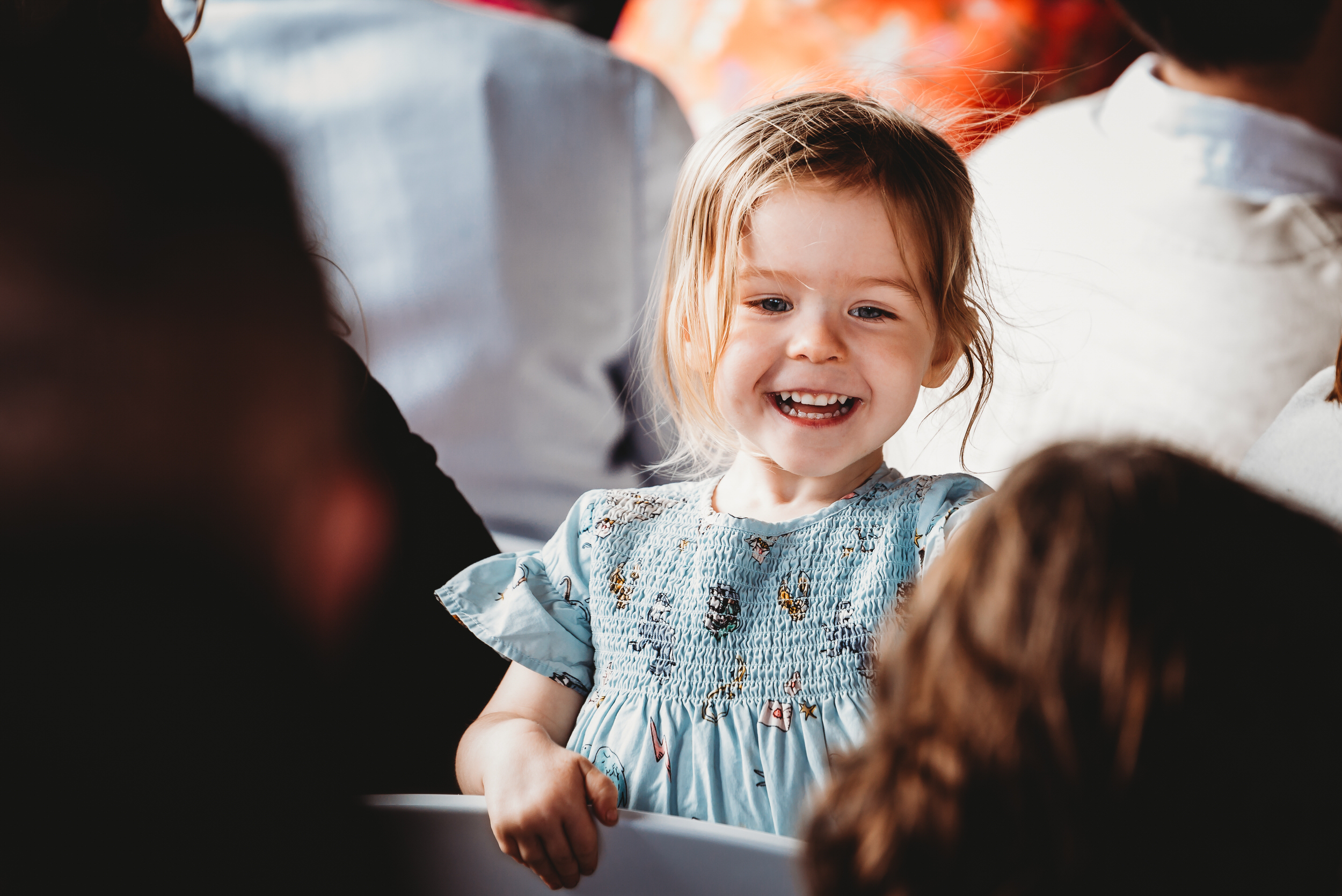 a little girl leaning over a chair and laughing  during a wedding 