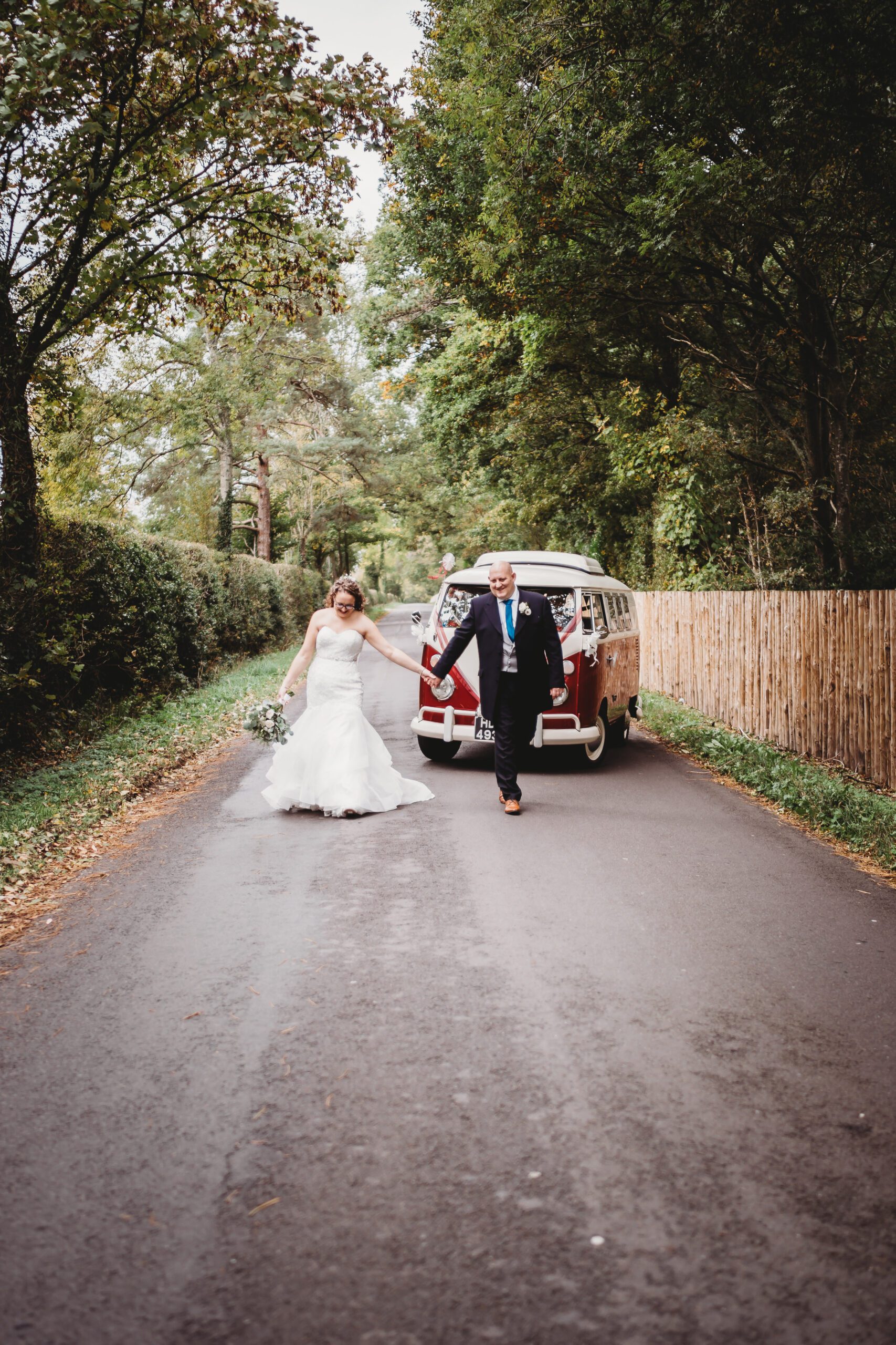 a bride and groom walking and posing in front of their wedding vw van taken by a hampshire wedding photographer 