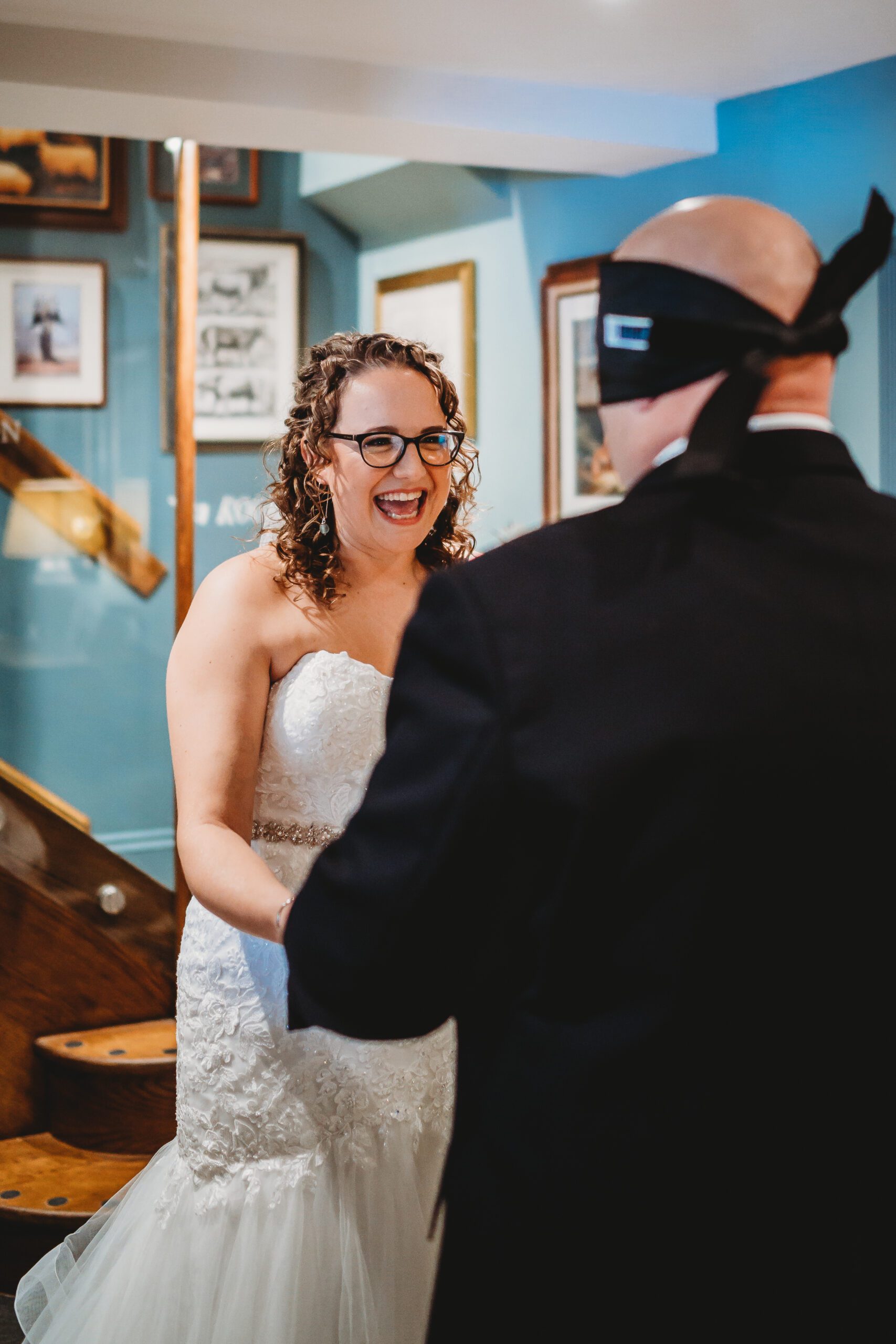 a bride smiling as she sees her husband for the first time whilst doing a  blind look