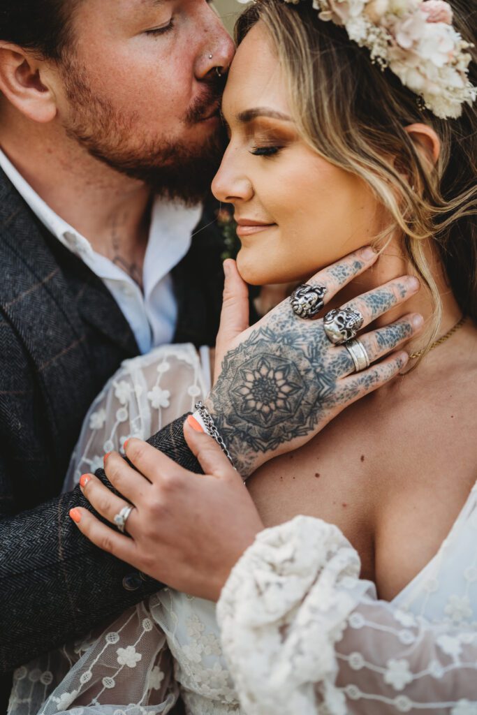 a close up of a groom gently stroking his wifes cheek