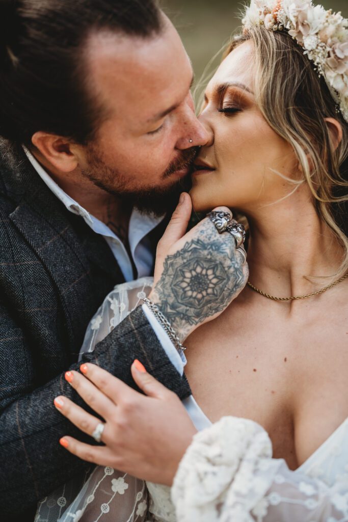 a close up of a groom gently kissing his wife following their festival wedding