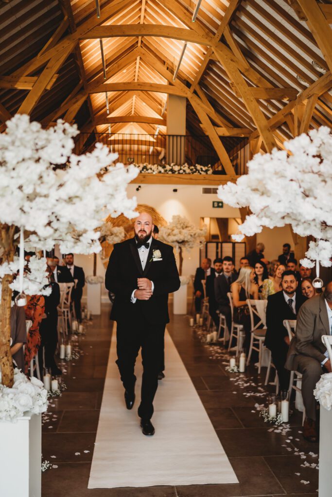 groom walking down the aisle to wait for his bride to be 