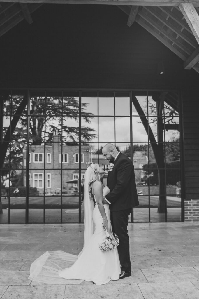 newly wed bride and groom in front of the big windows at the post barn newbury