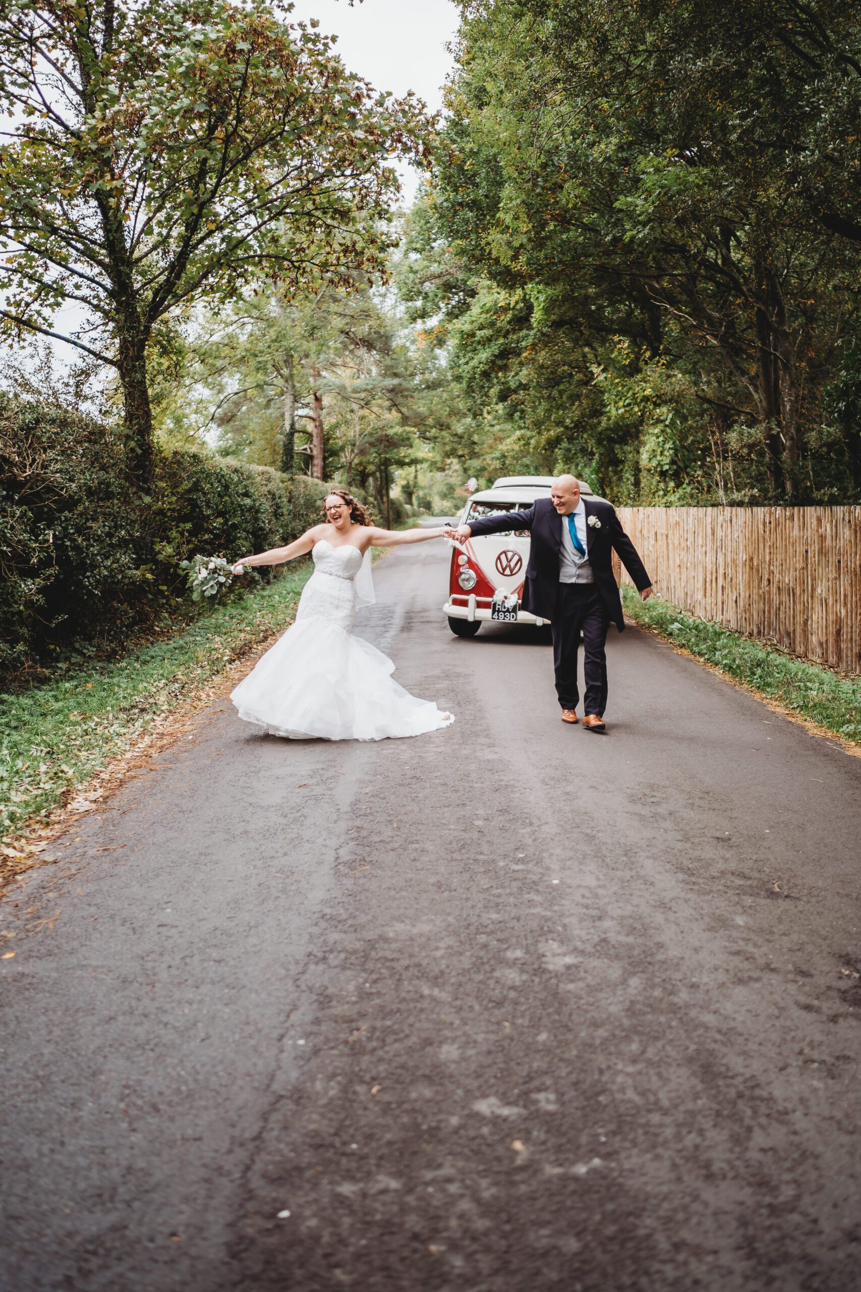 a bride and groom walking and posing in front of their wedding vw van taken by a hampshire wedding photographer 