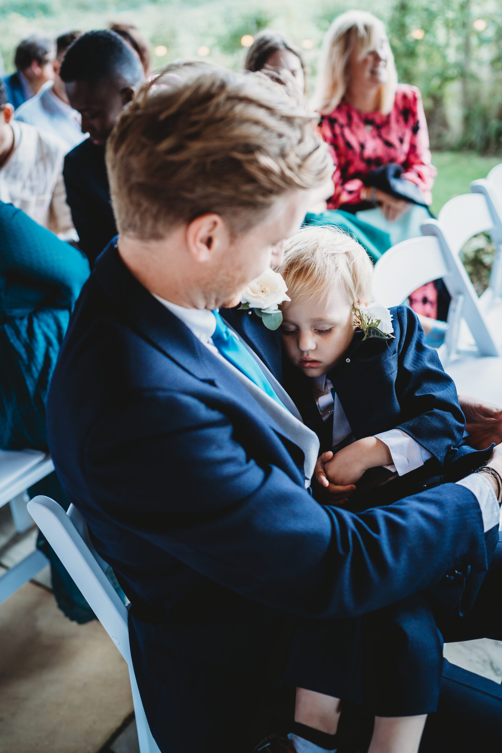 a page boy asleep on an ushers lap during a wedding service 