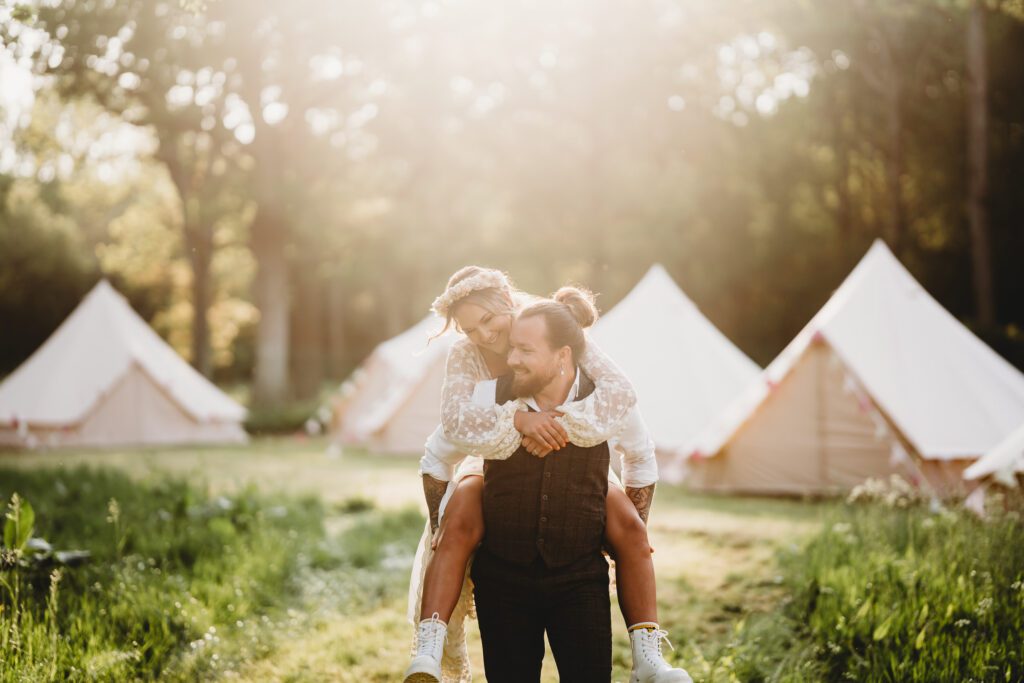 a groom giving his new bride a piggy back ride during their festival wedding 