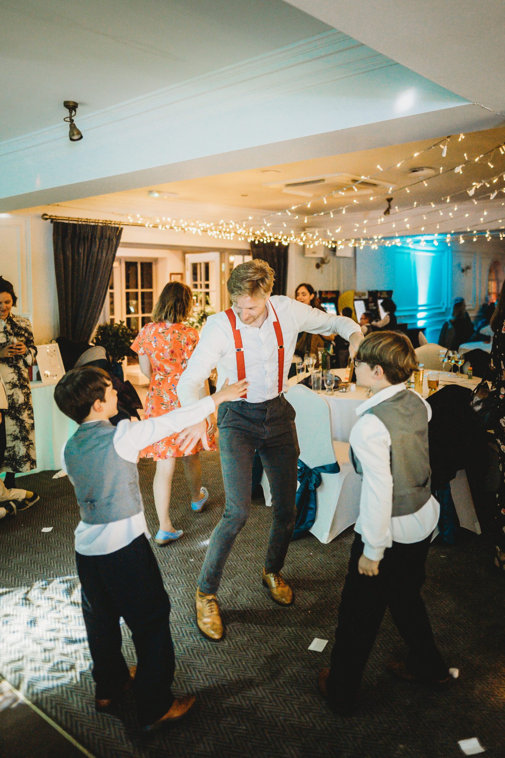 an usher dancing with 2 page boys for a wedding reception 