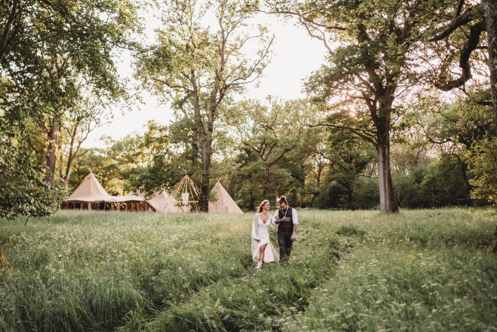 a bride and groom walking through long grasses for a festival wedding photographer 