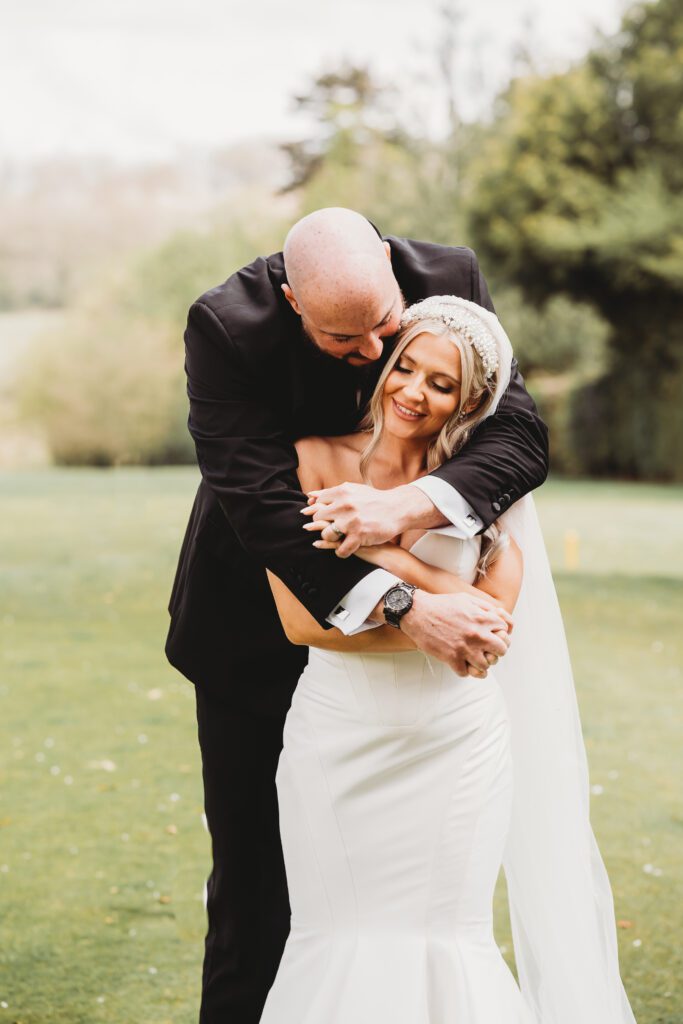 a groom cuddles his bride from behind