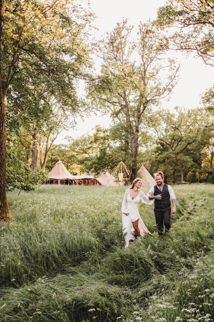 a bride and groom walking through long grasses for a festival wedding photographer 