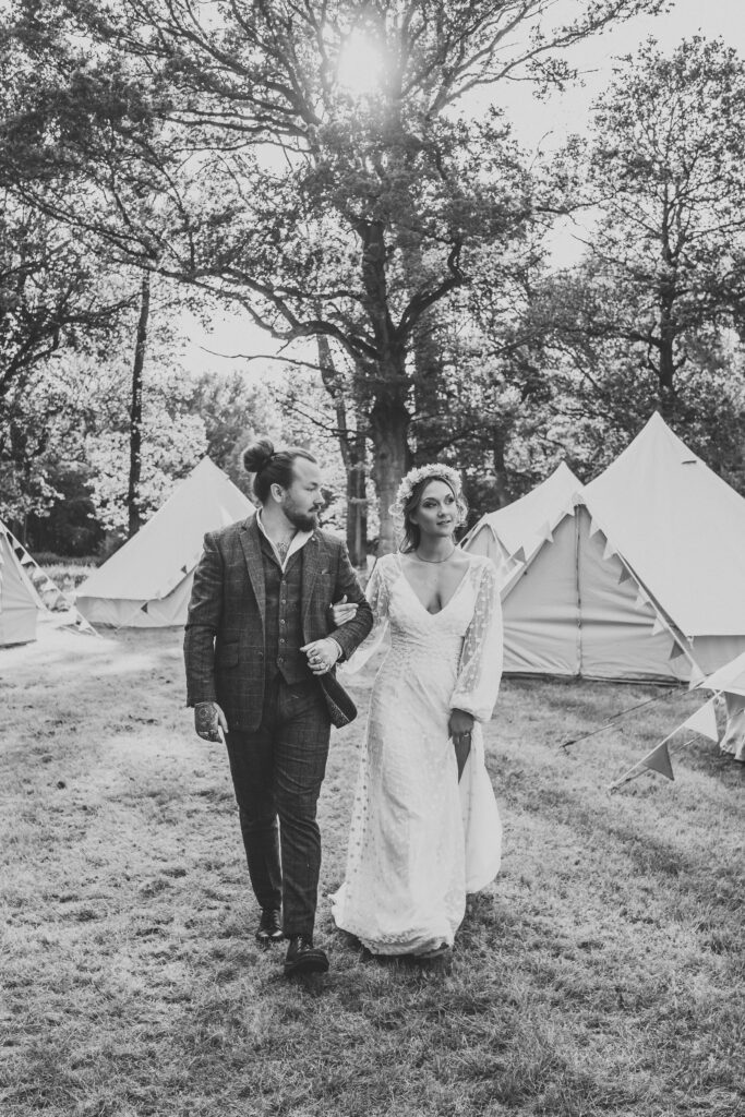 a black and white image of a bride and groom linking arms and walking for an alternative wedding photographer 