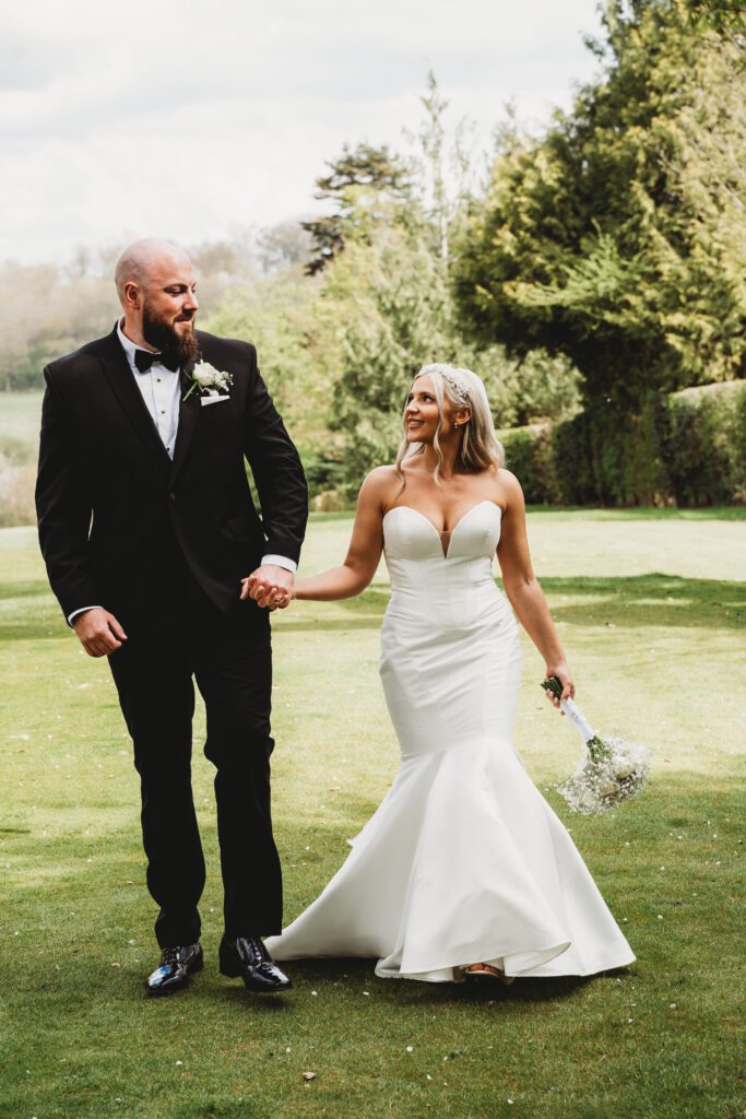 a bride and groom walk hand in hand following their ceremony