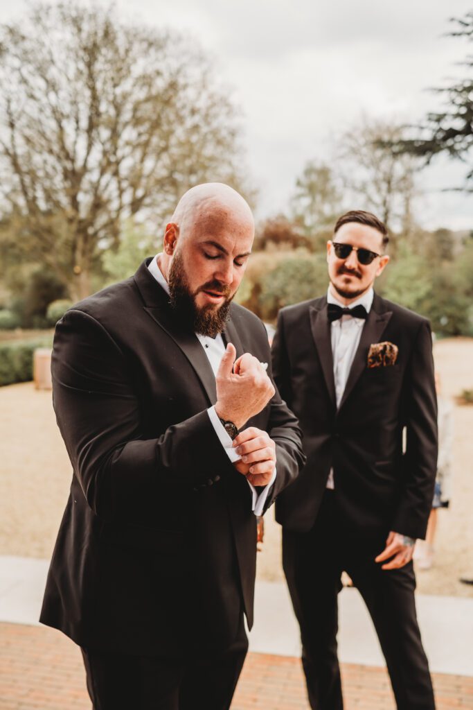 The best man adjusting his cufflinks before his wedding at the post barn newbury