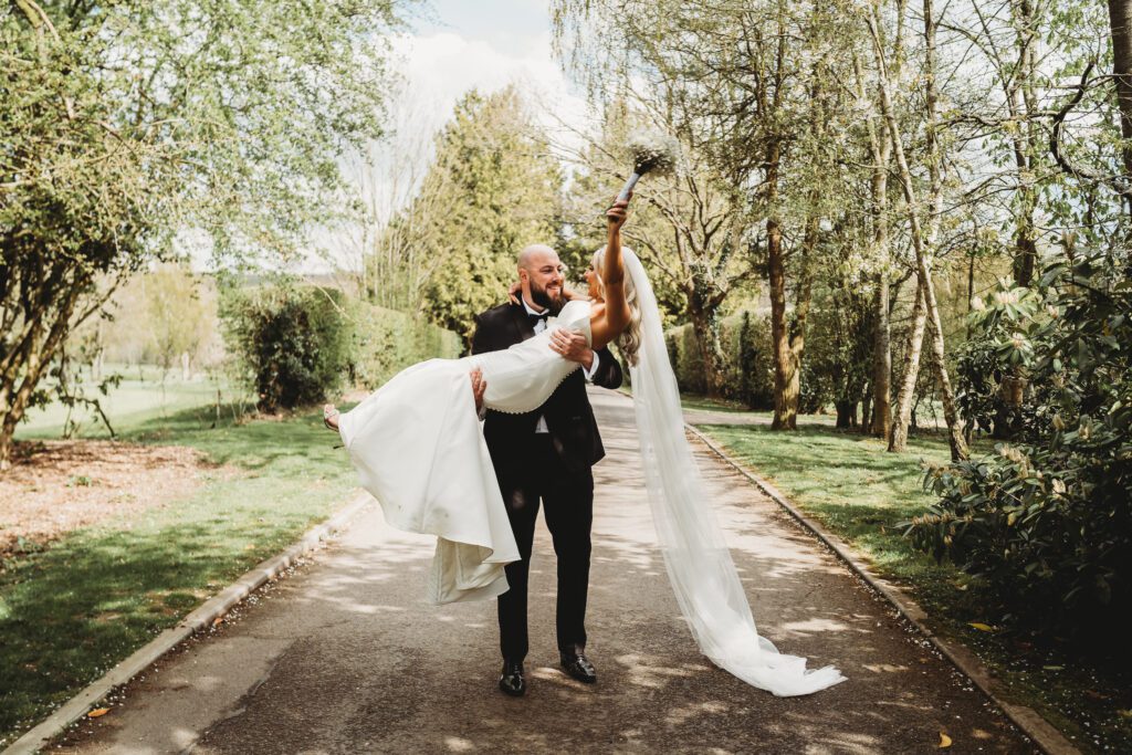 a groom picking up his newly wed wife after their ceremony