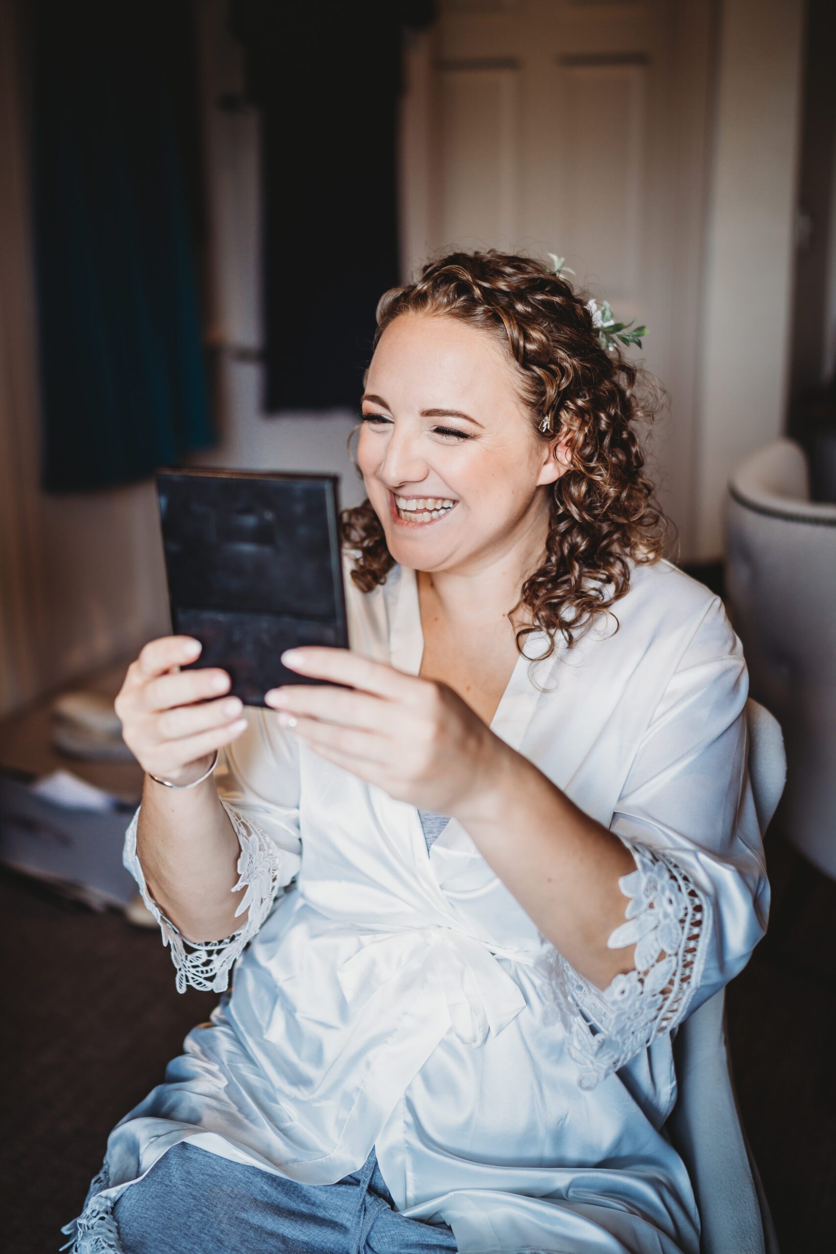 a bride looking at her finished make up and smiling