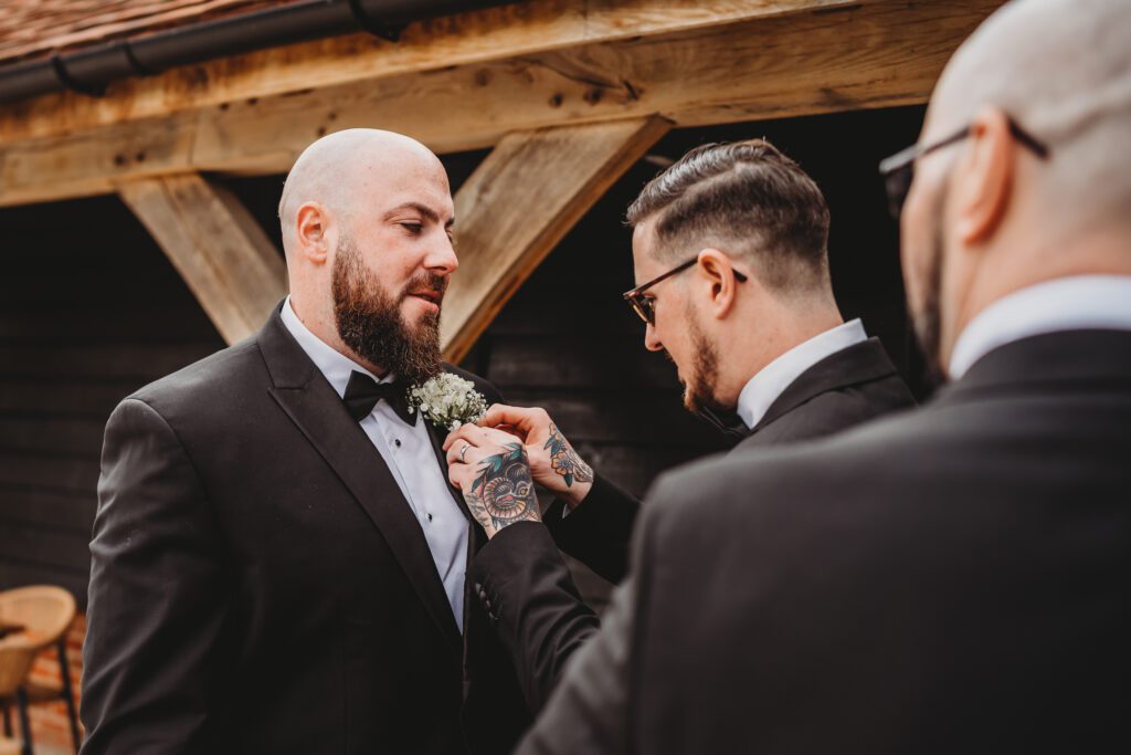 The usher helping the groom do his button hole for a newbury wedding photographer 