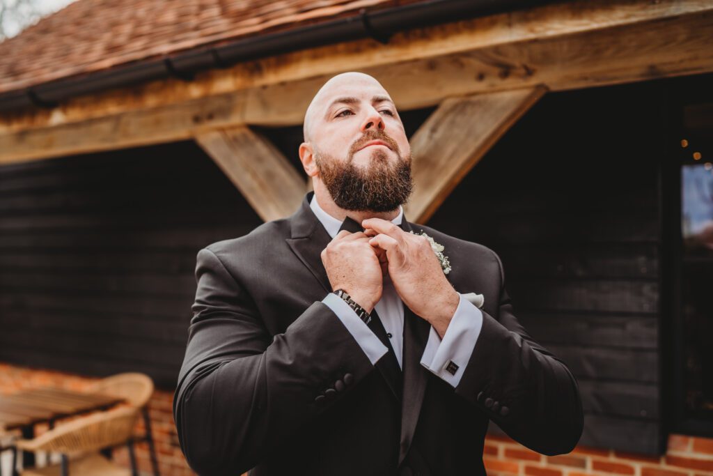 The usher helping the groom do his button hole for a newbury wedding photographer 