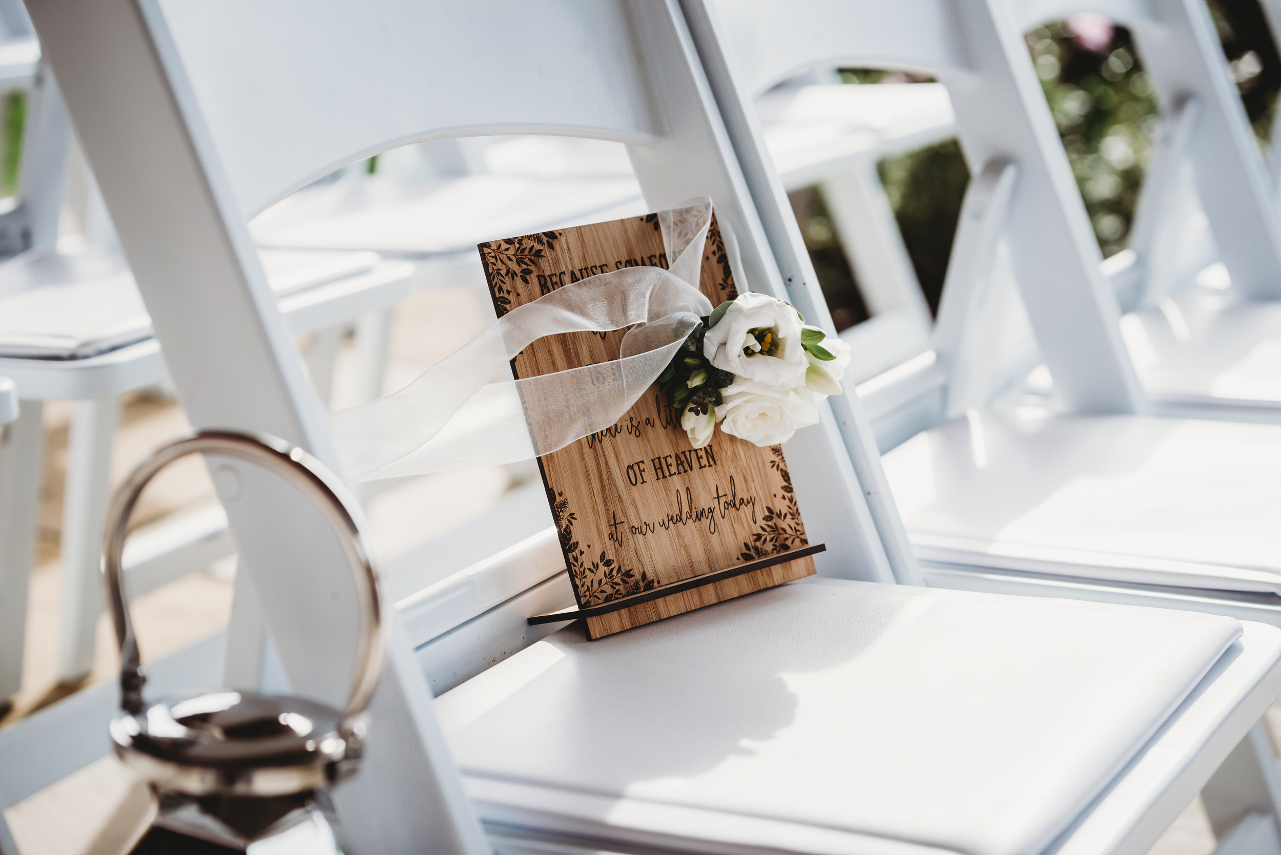 a wooden sign placed on a chair at the wedding ceremony, there to acknowledge those that cant be with them