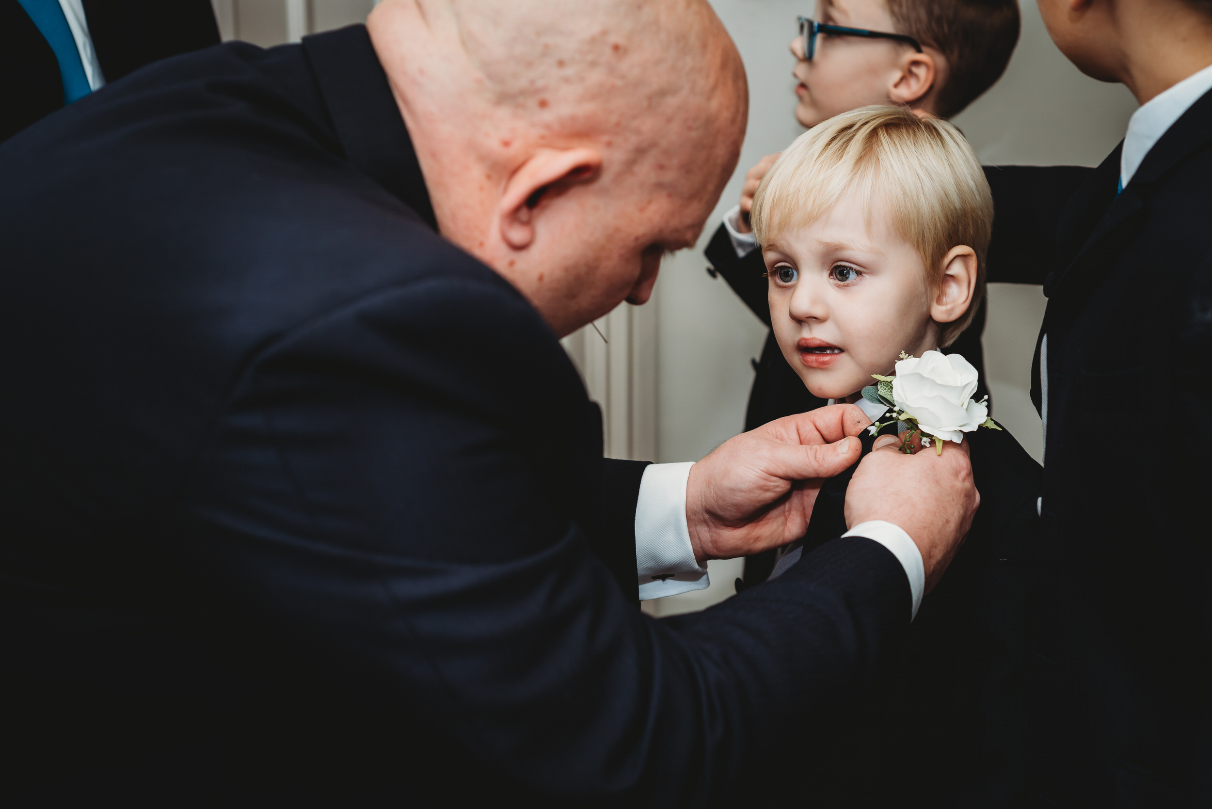 a groom putting a button hole on a page boys lapel for a hampshire wedding photographer