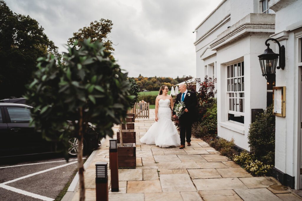 a bride and groom walking and chatting in front of the wellington arms, their wedding venue