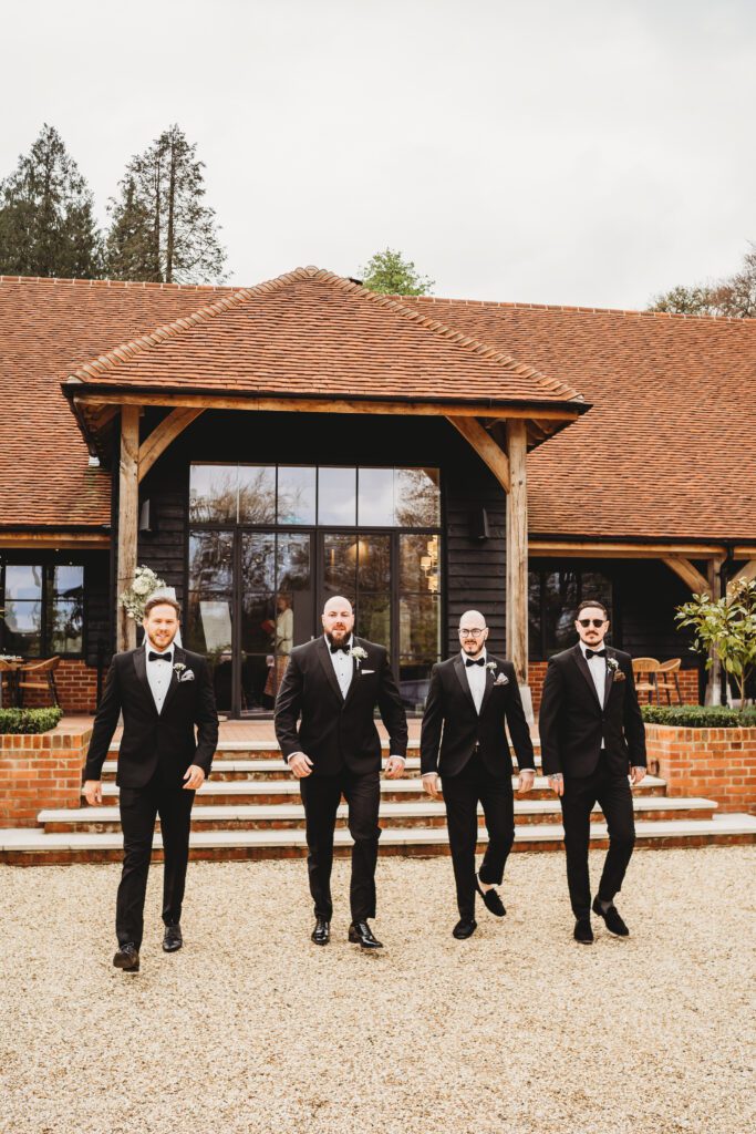 the grooms men walking towards a berkshire wedding photographer at the post barn newbury 