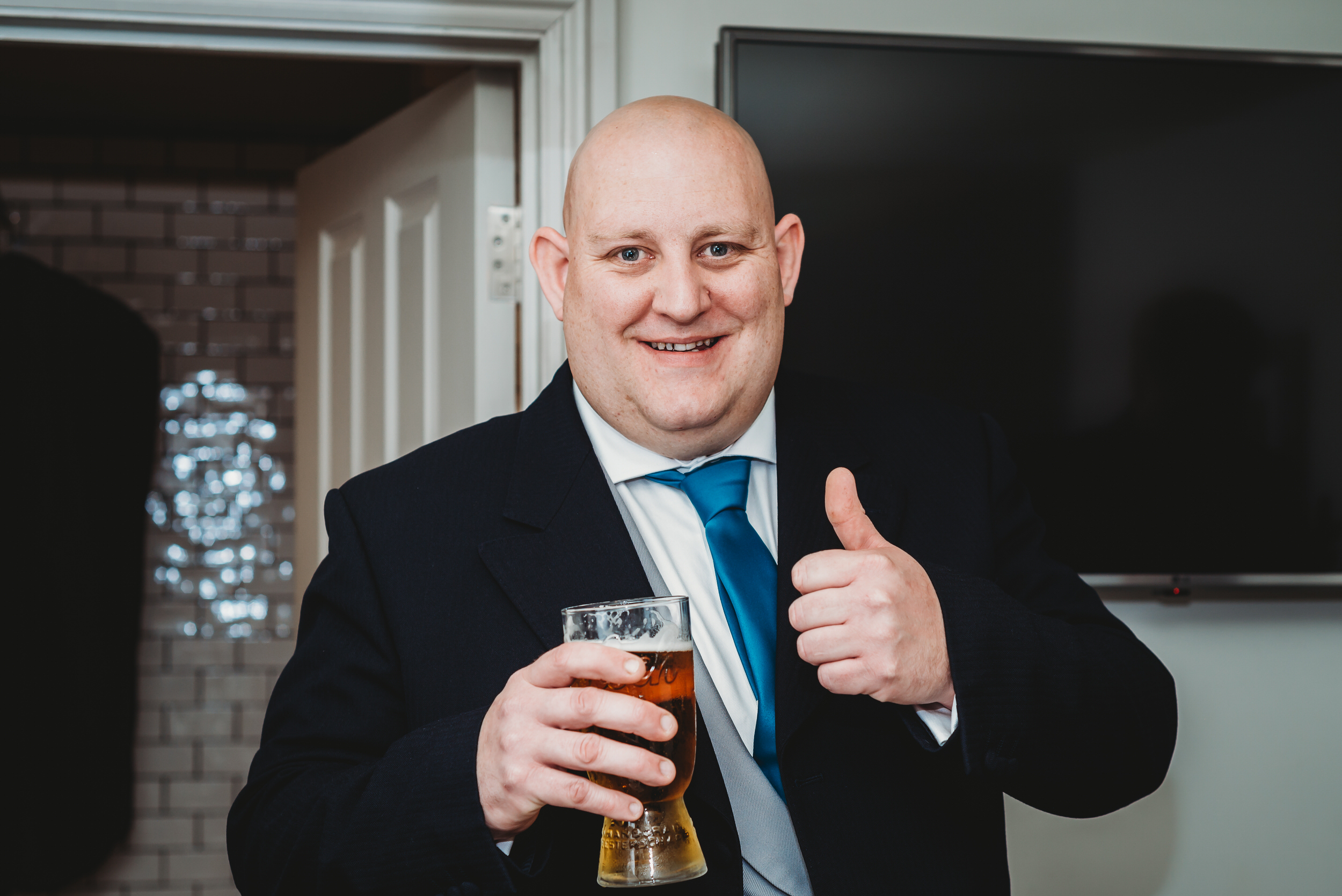 a groom smiling and putting his thumb up with a pint in his hand