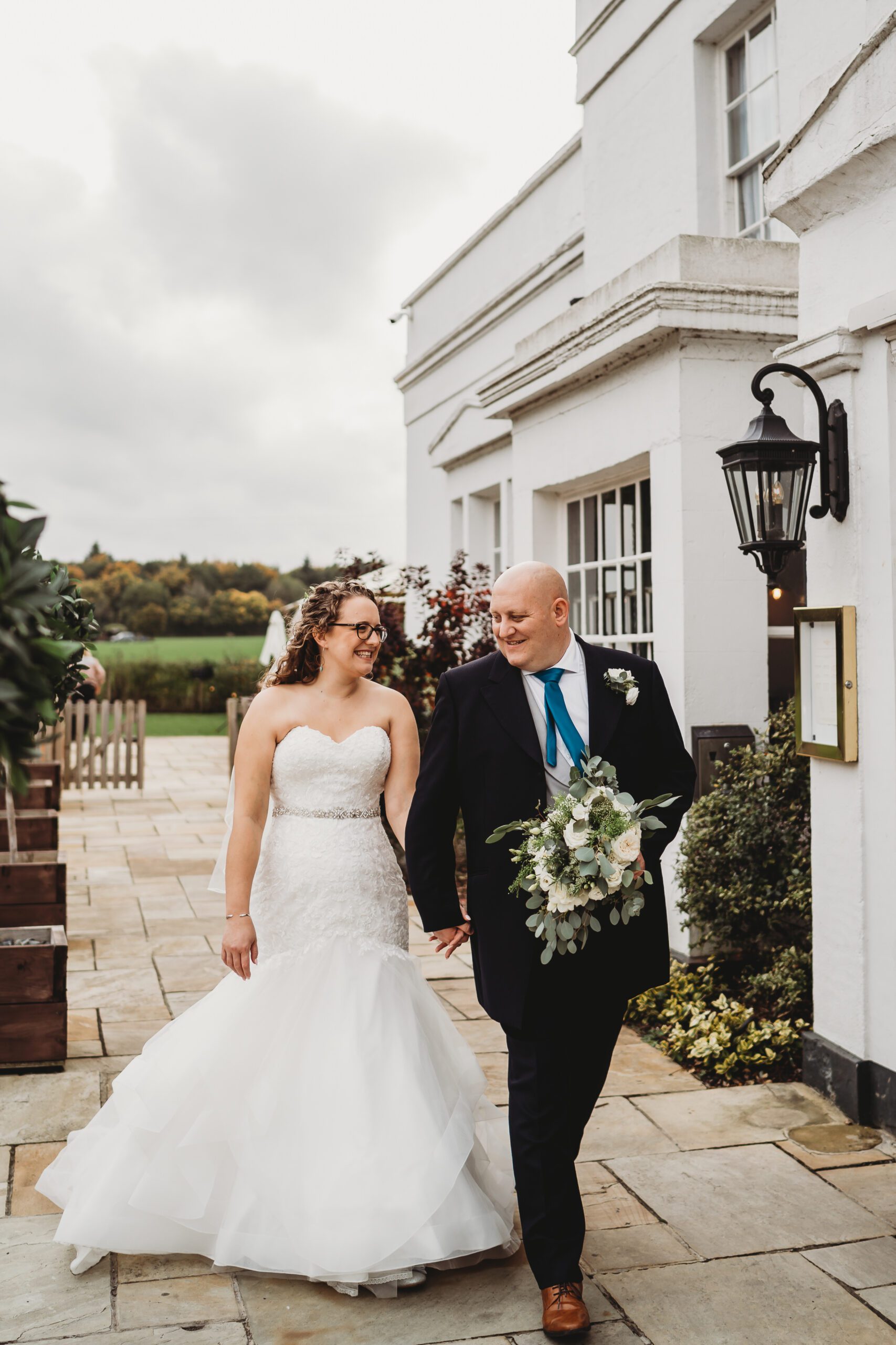 a bride and groom walking together in front of their wedding venue 