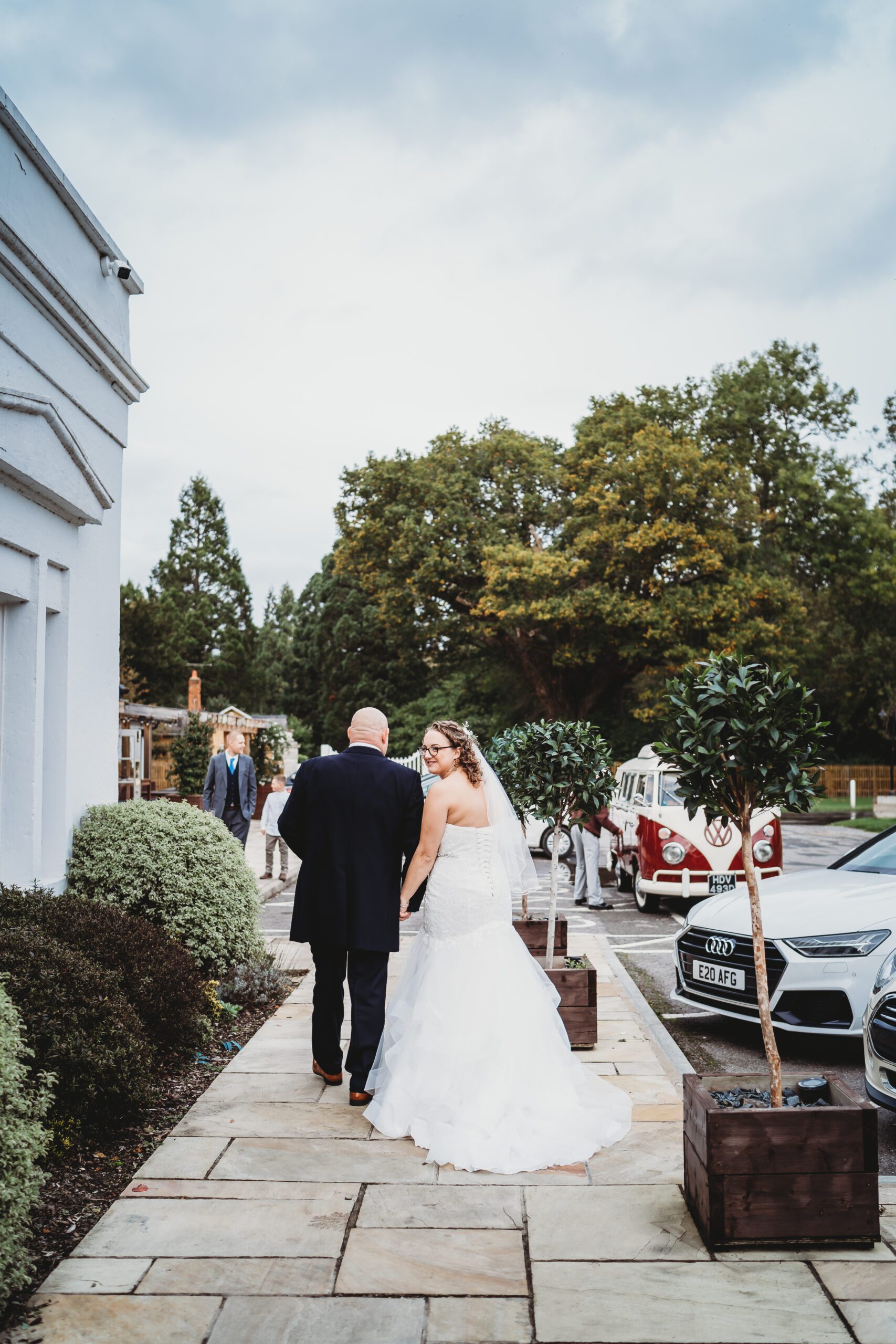 a bride and groom walking away whilst the bride looks back at a hampshire wedding photographer