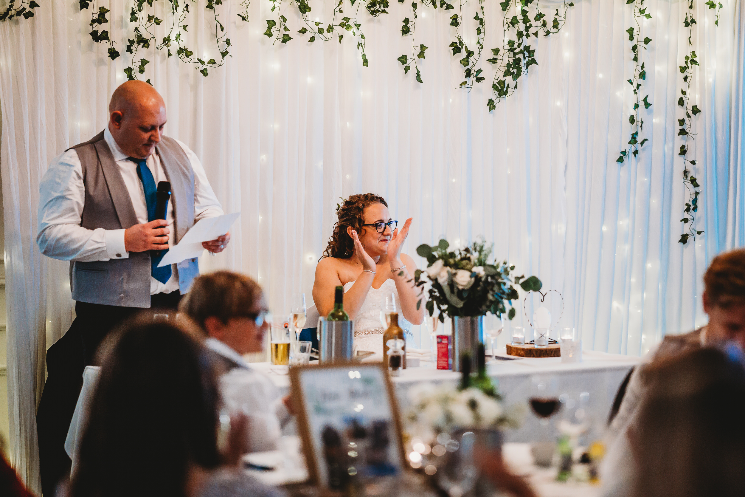 a bride clapping during her new husbands speech taken by a hampshire wedding photographer 