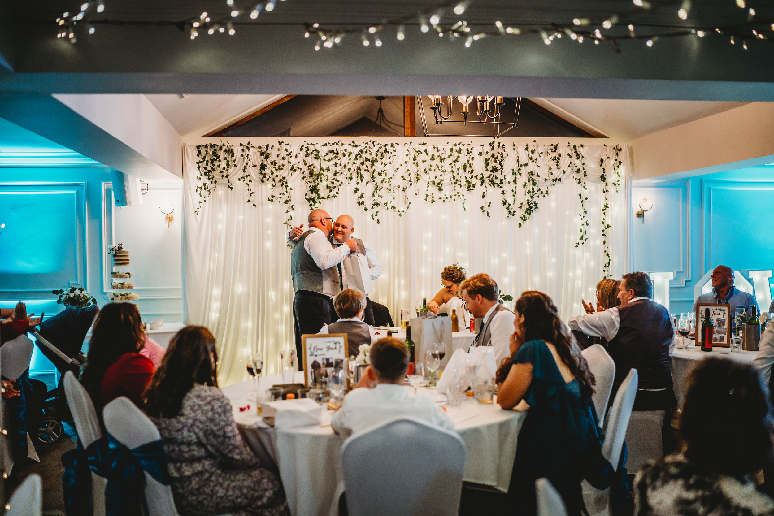a groom and his best man hugging during the wedding speeches 
