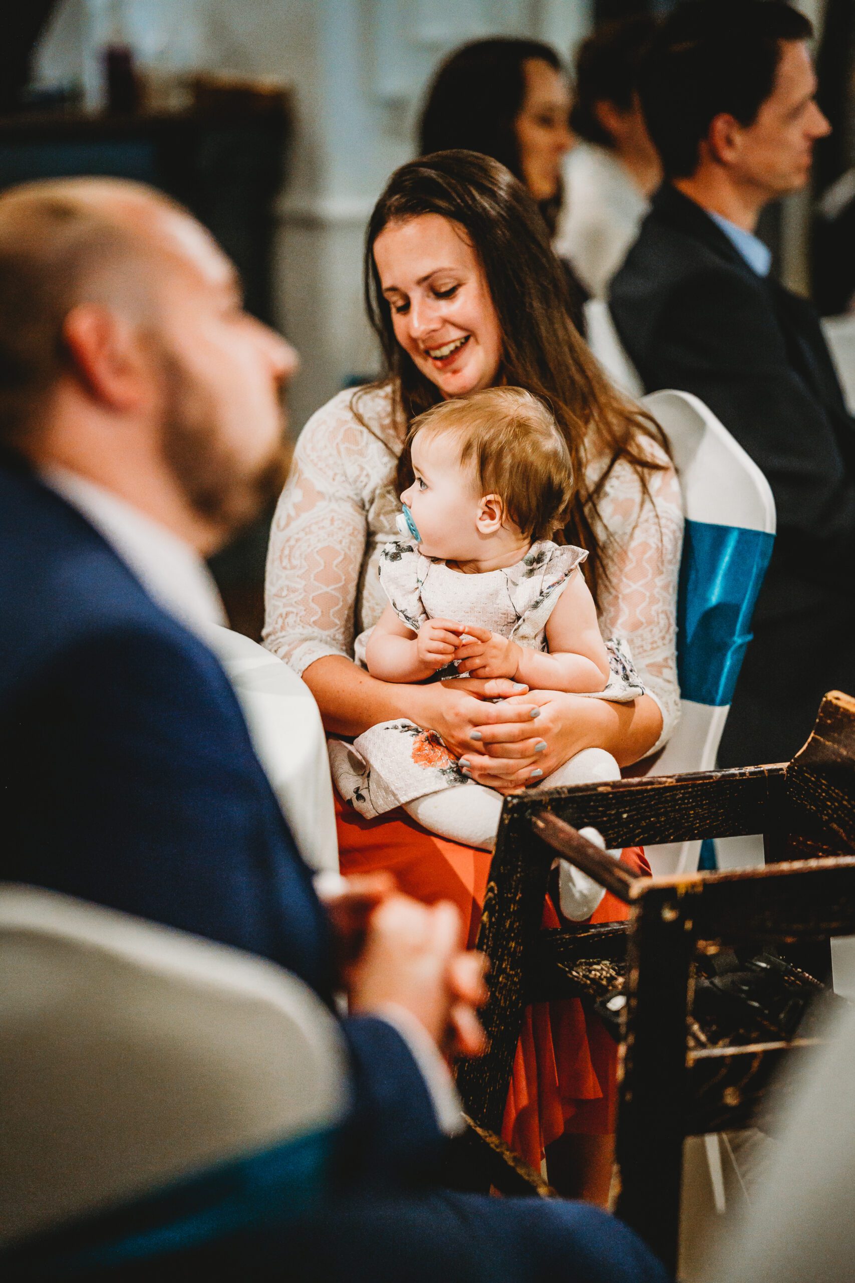 a child sat on her mums lap for a wedding reception