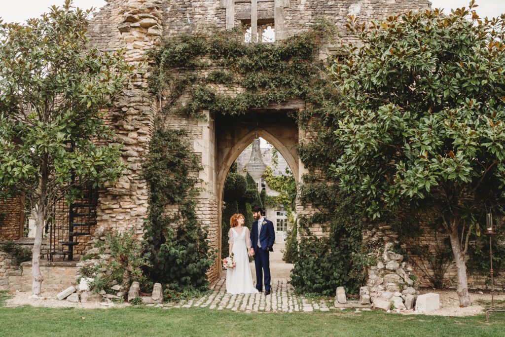 a bride and groom stood under the ruins at Euridge Manor after their wedding taken by a euridge manor wedding photographer 