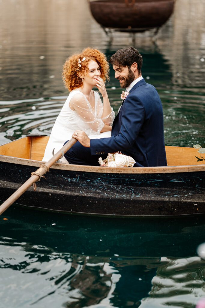 a bride giggling as her new husband tries to row a boat on a lake at euridge manor for a wedding photographer 