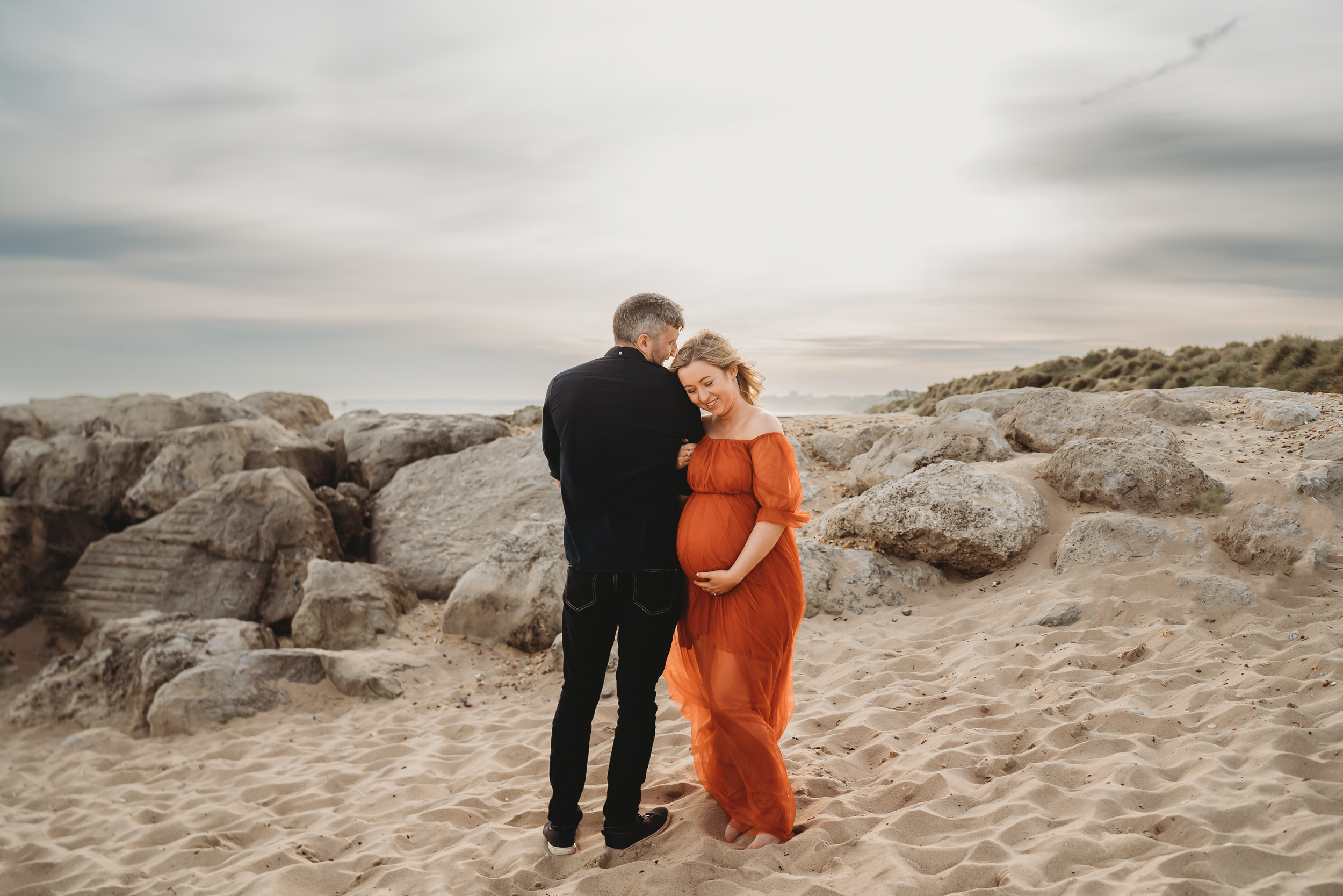 a husband and wife linking arms and looking at each other for a newbury maternity photographer