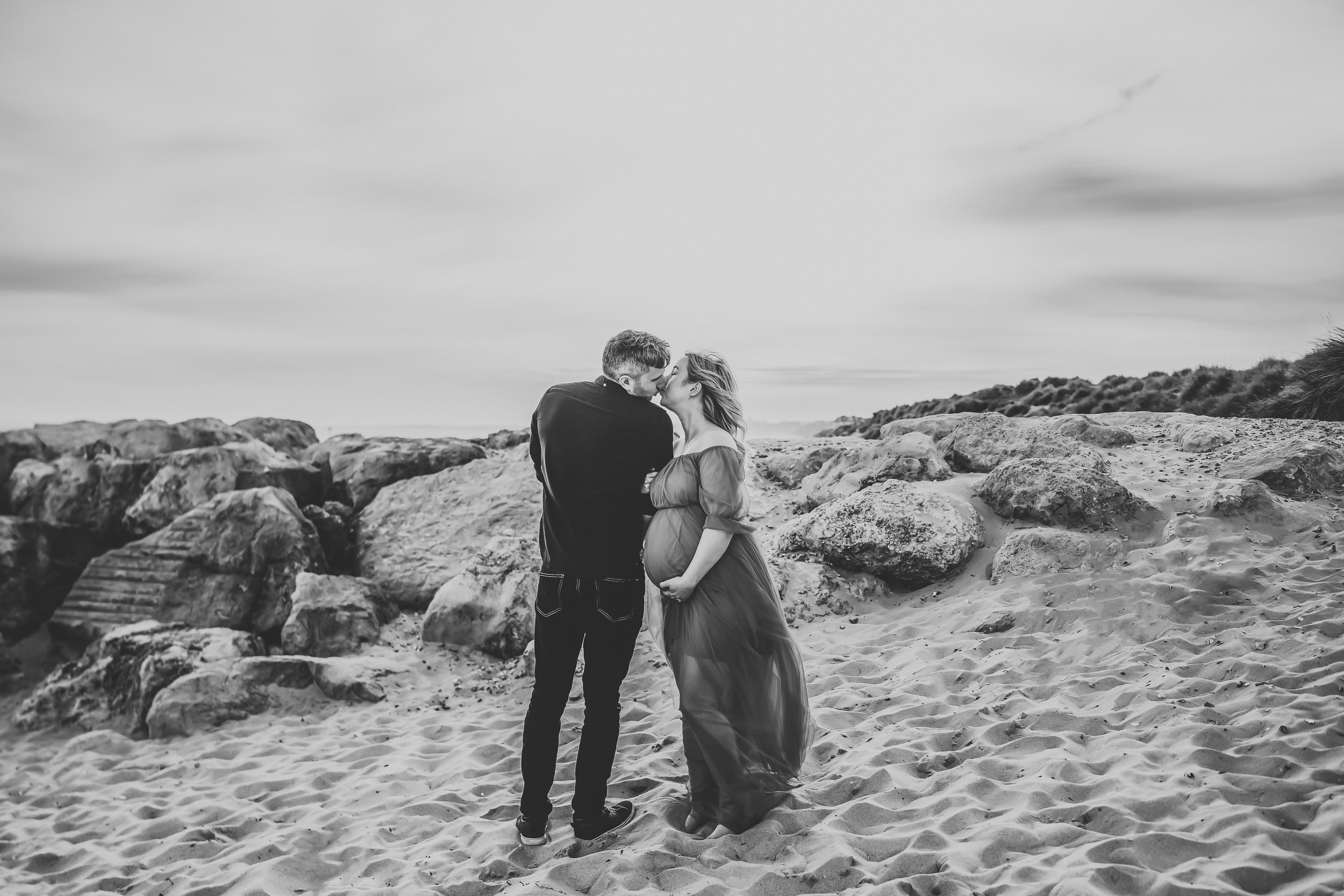 a husband and wife linking arms and looking at each other for a newbury maternity photographer