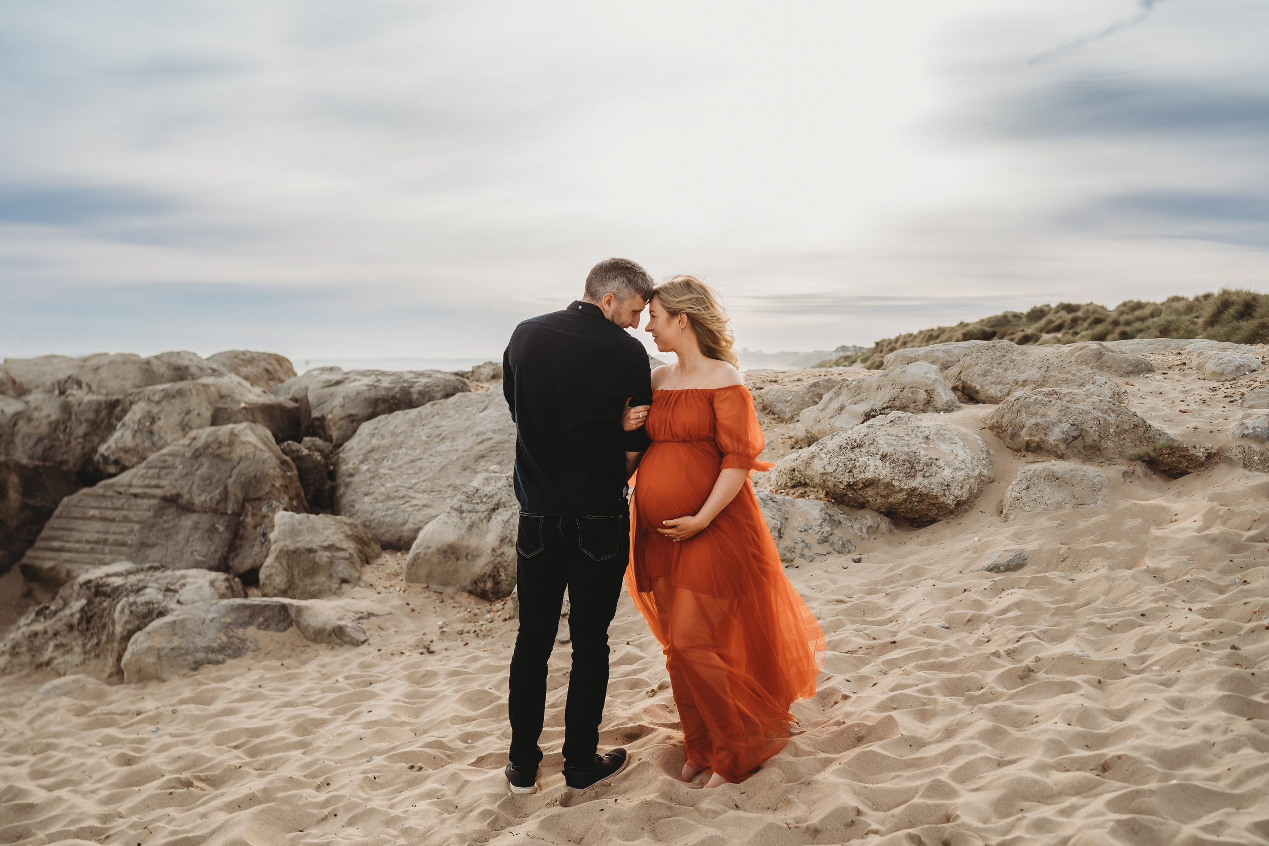 a husband and wife linking arms and looking at each other for a newbury maternity photographer