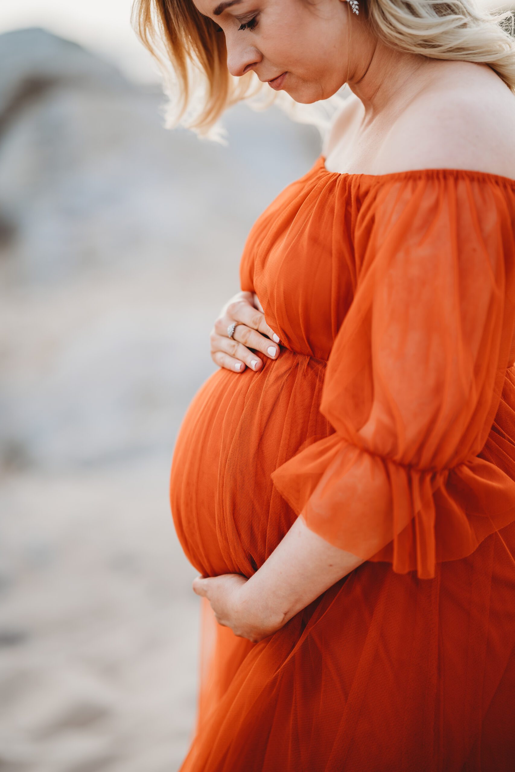 a pregnant ladies expectant tummy in her bright orange dress