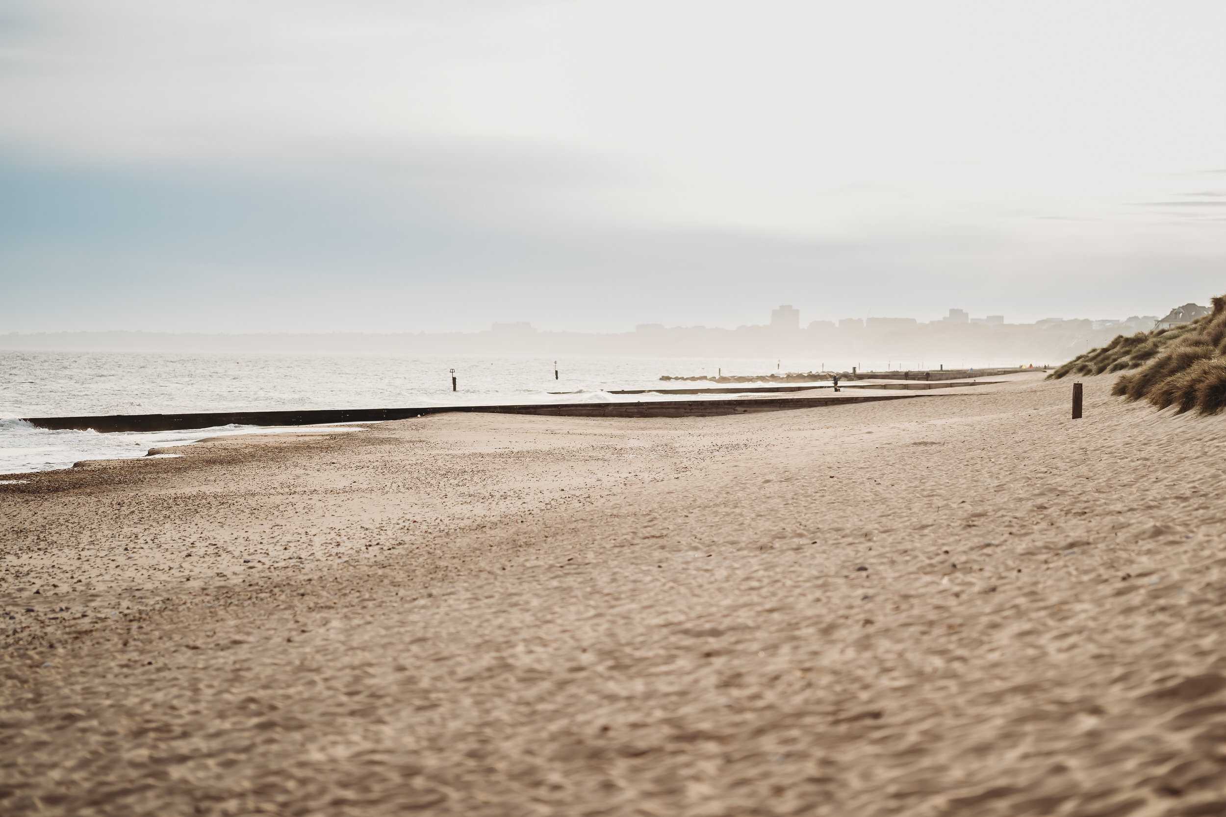 hengistbury head at sunset with the misty buildings in the background