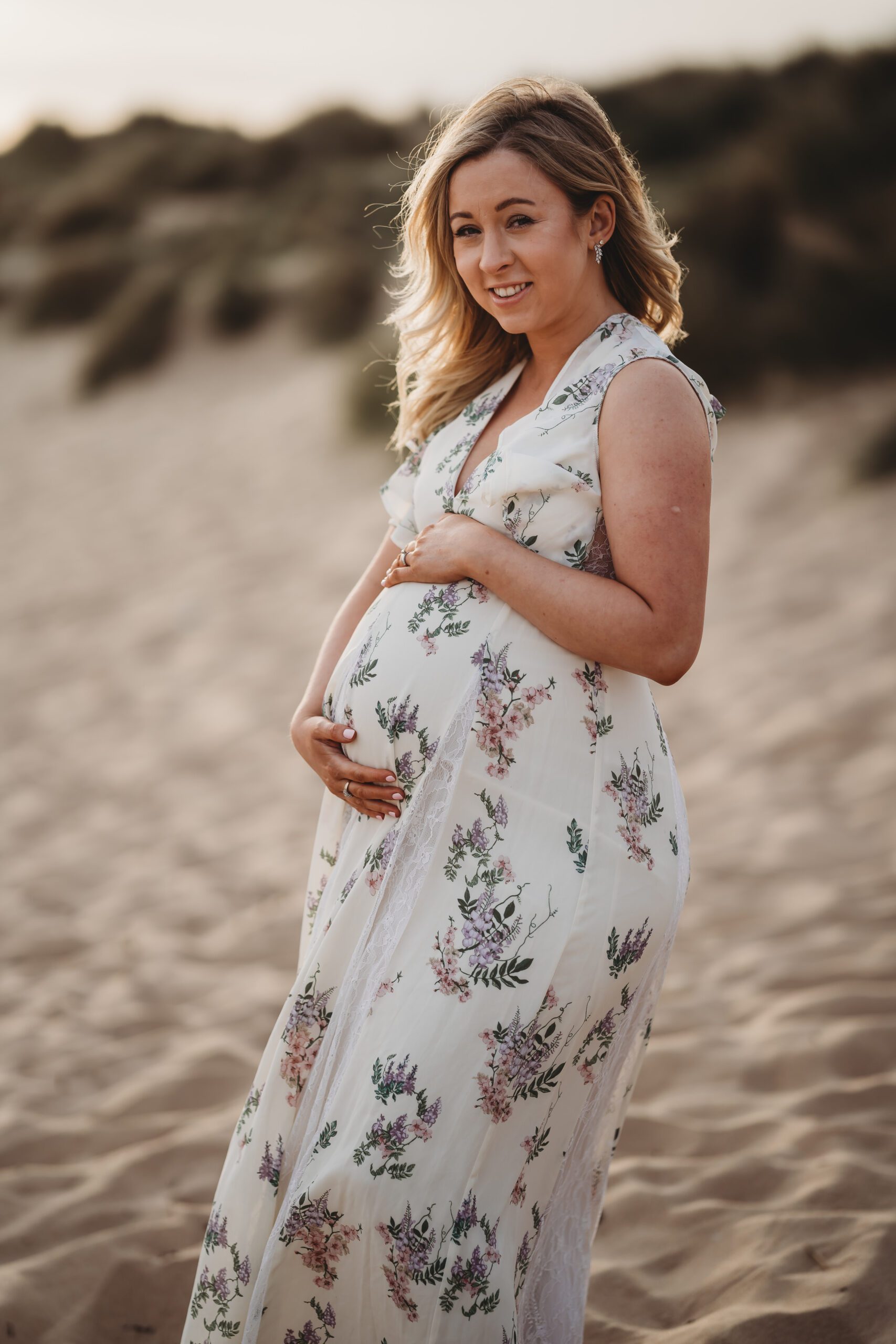 a pregnant lady cuddles her bump and smiles for a maternity session