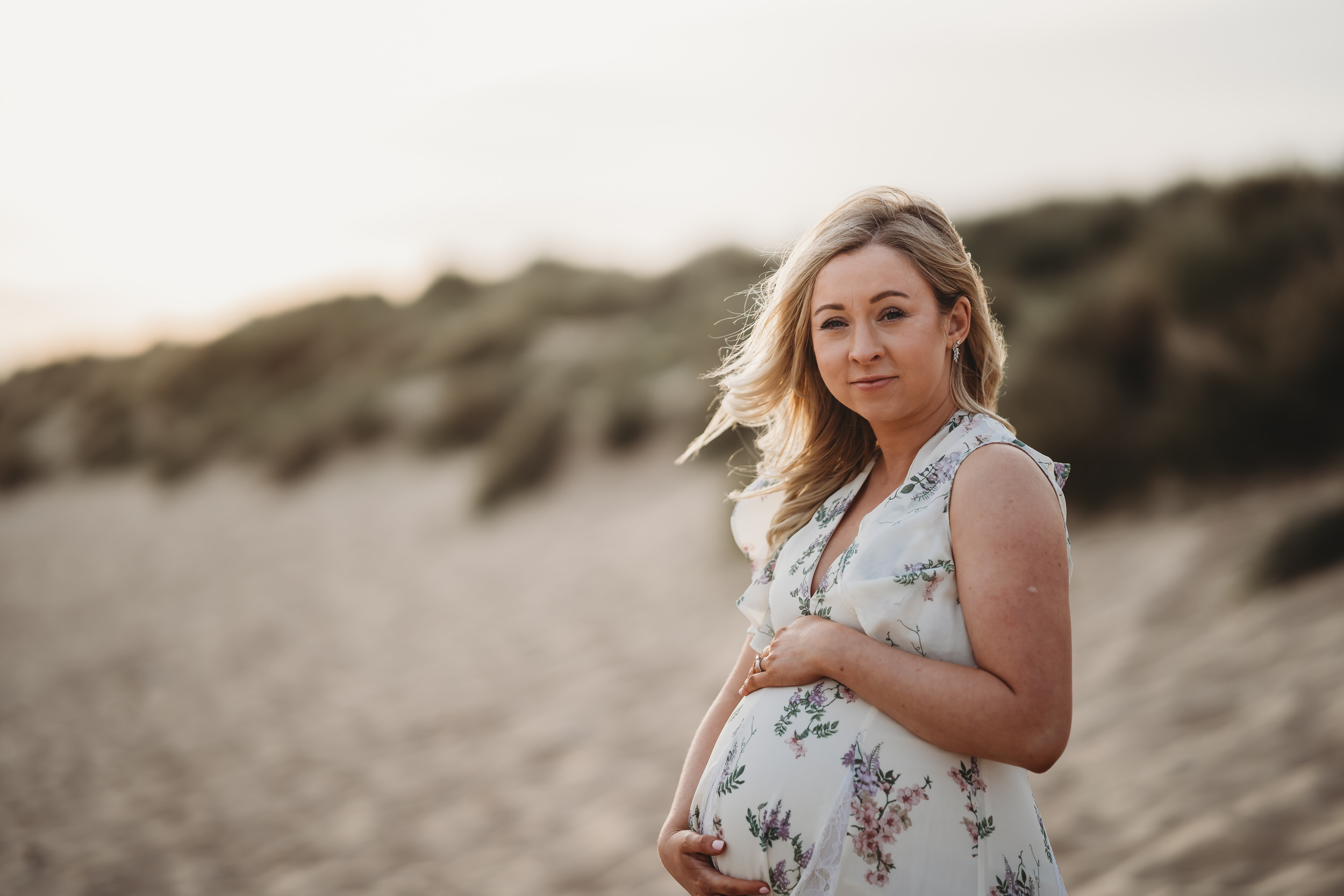 a pregnant lady cuddles her bump as she poses for a newbury maternity photographer