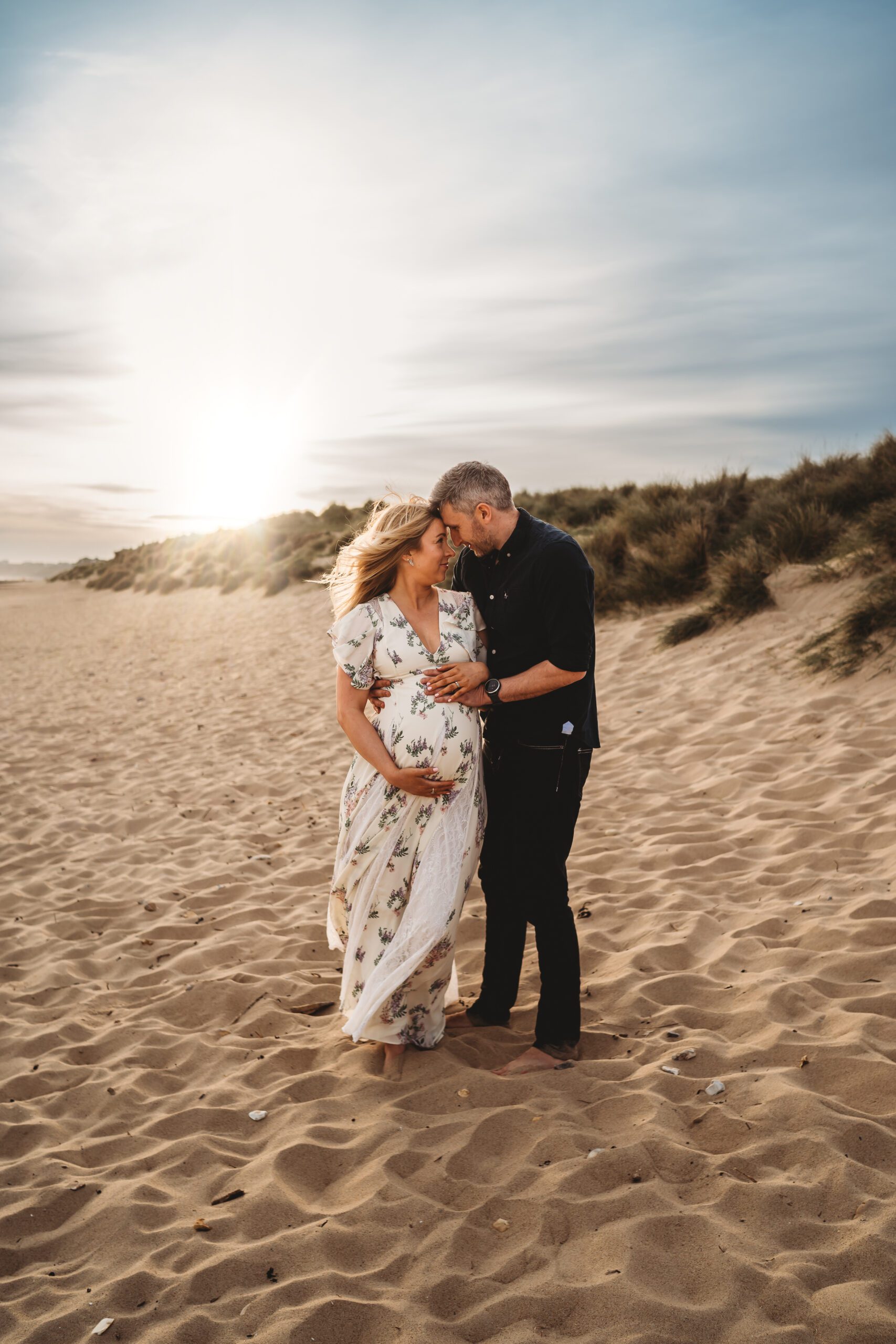 a husband touches foreheads with his pregnant wife and cuddles on her tummy for a newbury maternity photographer