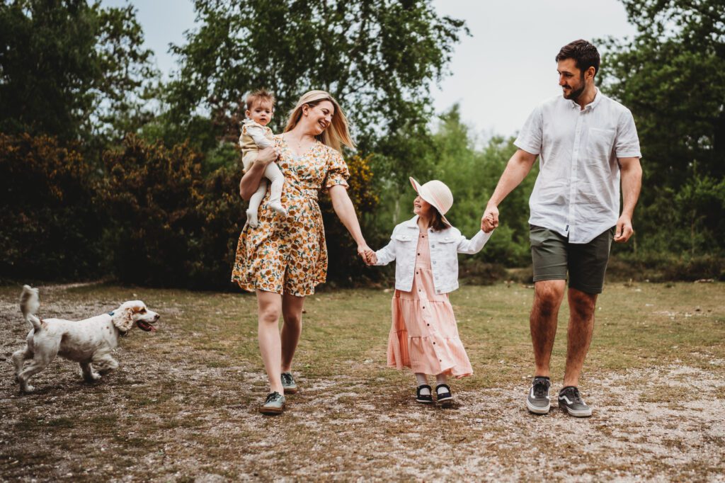 Mum, Dad and 2 children holding hands and walking towards a family newbury photographer