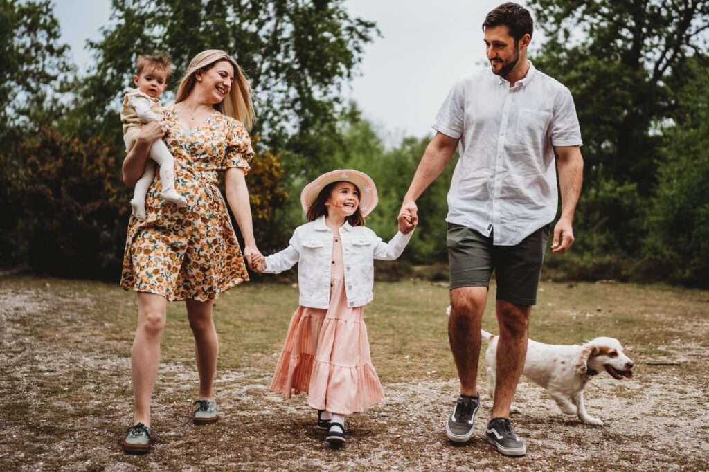 Mum, Dad and 2 children holding hands and walking towards a family newbury photographer