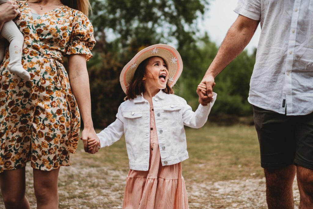 a little girl holding her parents hands as she looks up smiling