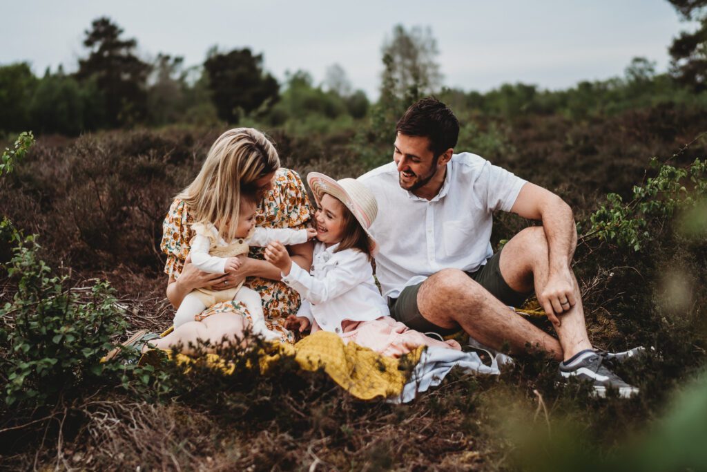 a family of 4 sat down laughing and chatting for a summer family photoshoot in Newbury