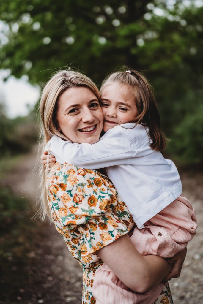 a little girl hugging on to her mum tightly as she smiles happily