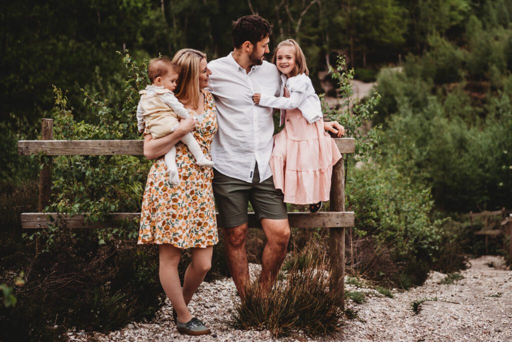 a family of 4 chatting whilst leaning against a gate for a newbury family photoshoot