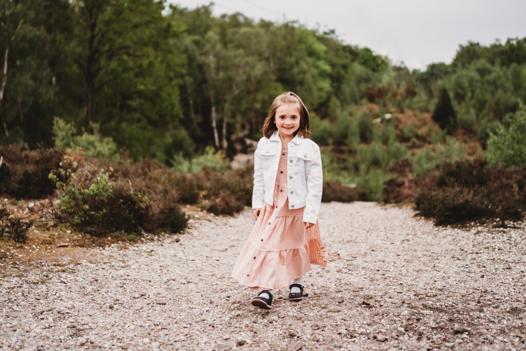 a little girl dressed in a pink dress smiling at a newbury family photographer