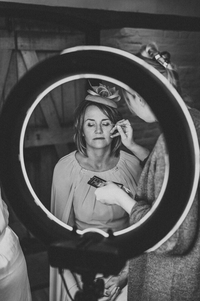 mother of the bride having her make up done as seen through a make up artists ring mirror