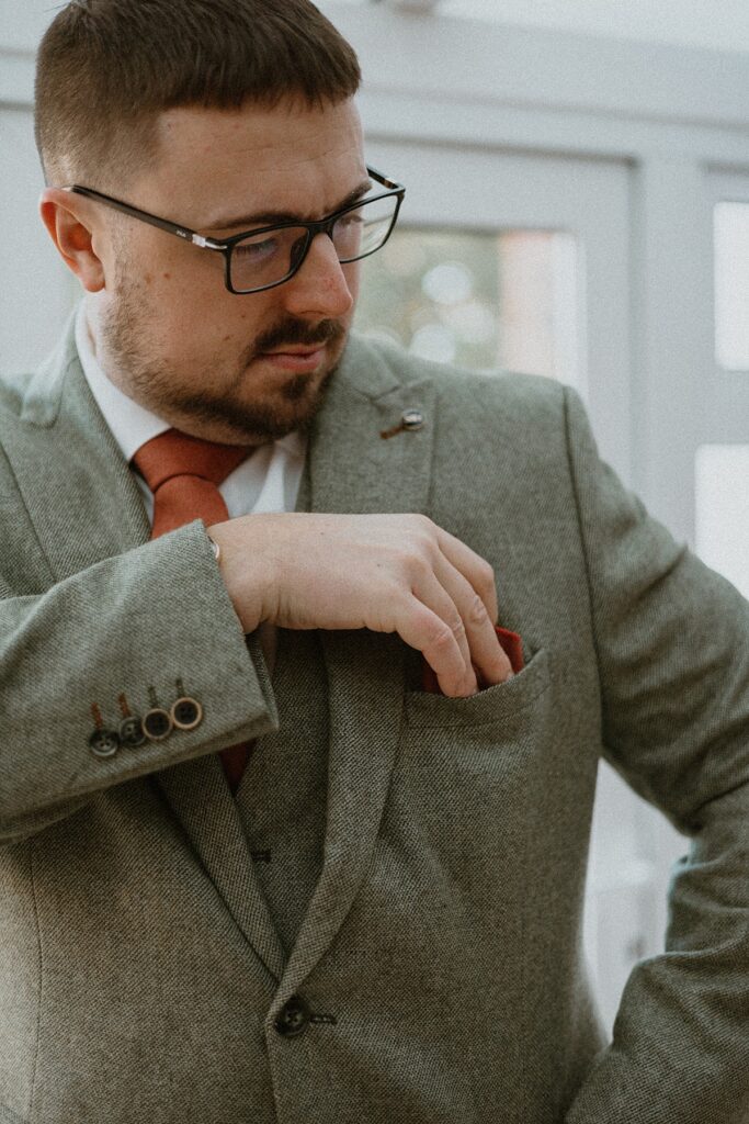 a groom arranging his pocket square before his wedding